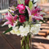Pink lilies and roses in a clear glass vase with white hydrangeas