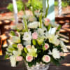 Pink roses and white lilies arranged in a clear glass bowl