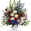Mixed red, white, and blue floral arrangement in a white vase
