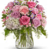 Pink and lavender roses with small purple daisies in a glass vase