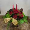 Low red and green holiday centerpiece with roses, candles, pinecones and a gold bow in a pedestal bowl