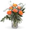 Orange roses in a clear glass vase with airy greenery