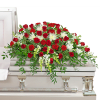 Red roses and white flowers arranged on a white casket