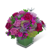 Pink and purple floral arrangement in a clear square vase