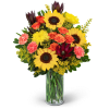 Sunflowers, orange roses, and pink carnations in a glass vase