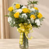 Yellow and white rose bouquet in a glass vase with a yellow plaid ribbon