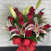 Bouquet of red roses and pink lilies in a glass vase with a red ribbon