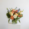 With pops of blue and orange, stunning imported Ranunculus and Roses make