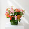 Pink and orange mixed bouquet in a green glass vase