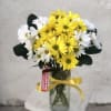 Bouquet of yellow and white daisies in a glass vase with a yellow ribbon
