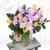 Pink and yellow roses with lavender daisies in a glass vase