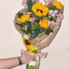 Bouquet of yellow sunflowers and pink alstroemeria wrapped in paper