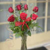 Red roses arranged in a clear glass vase with a red ribbon