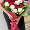 Bouquet of red and white roses wrapped in pink paper with a polka-dot ribbon