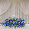 Low floral arrangement with vivid blue orchids and greenery on a wedding table