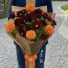 Bouquet of burgundy daisies and orange marigolds wrapped in brown paper