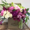 Mixed pink, white, and purple flowers arranged in a box