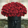 Red roses arranged in a black round box with a ribbon