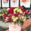 Mixed roses and tulips arranged in a pink hatbox