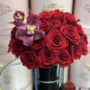 Red roses with two purple orchids in a black vase