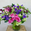 Pink roses and purple flowers arranged in a glass vase