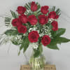 Red roses arranged in a clear glass vase with baby's breath