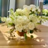 White roses and orchids arranged in a glass compote vase