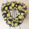 Heart-shaped floral wreath with cream roses, white blooms, and blue flowers