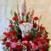 Large red and pink floral arrangement in a marbled vase