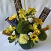 Yellow flowers and chocolate bars arranged in a green pot.