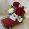 Red rose and daisy arrangement in a red toy car