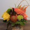 Mixed floral arrangement in a rustic bark container with yellow and orange blooms