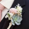 Boutonniere with pink and white roses and a succulent on a dark suit