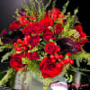 Red roses with dark calla lilies and berry accents in a vase