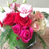 Bouquet of pink and red roses with pale pink blooms in a glass vase