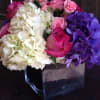 Bouquet of pink roses, white hydrangeas, and purple hydrangeas in a square vase