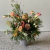 Mixed peach and coral flowers arranged in a gray pot