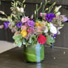 Mixed pink, purple, white, and yellow flowers in a glass vase