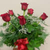 Red roses arranged in a glass vase with a red ribbon