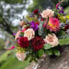 Bouquet of pink roses, burgundy blooms, and purple flowers