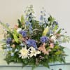 Large pastel floral casket spray with lilies, chrysanthemums, and blue delphinium