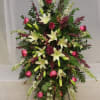 Standing floral spray with pink roses and white lilies on a black easel