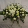 White rose and hydrangea floral arrangement with trailing greenery