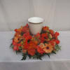 Orange floral wreath around a white urn-shaped vase