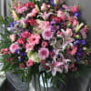 Large mixed bouquet with pink lilies, roses, and purple flowers in a white vase