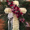 Cross-shaped floral tribute with white carnations, red roses, and pink orchids