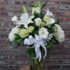 White floral arrangement with lilies, roses, and a ribbon bow