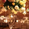 Tall floral centerpiece in a clear glass vase with hanging candle holders