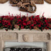 Long red floral arrangement displayed across a mantel