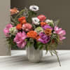 Mixed pink, orange, and white flowers arranged in a white vase